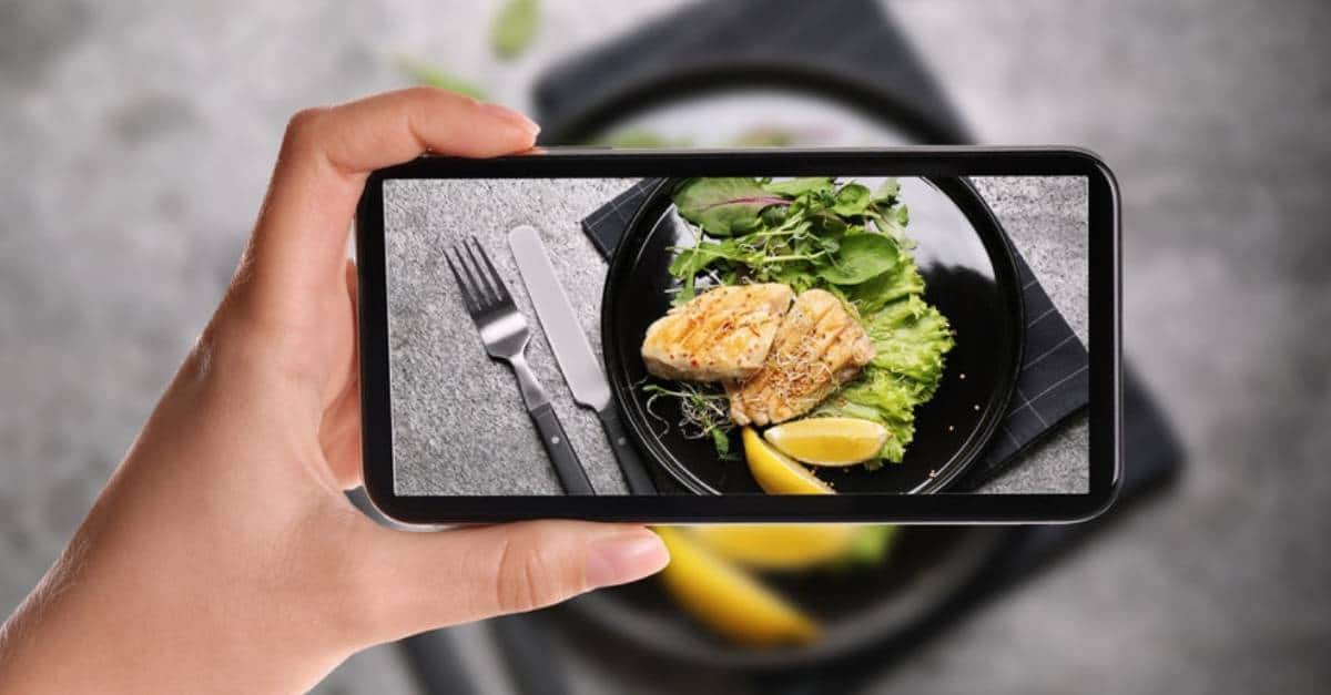 A food blogger taking a picture with their phone of an entree.