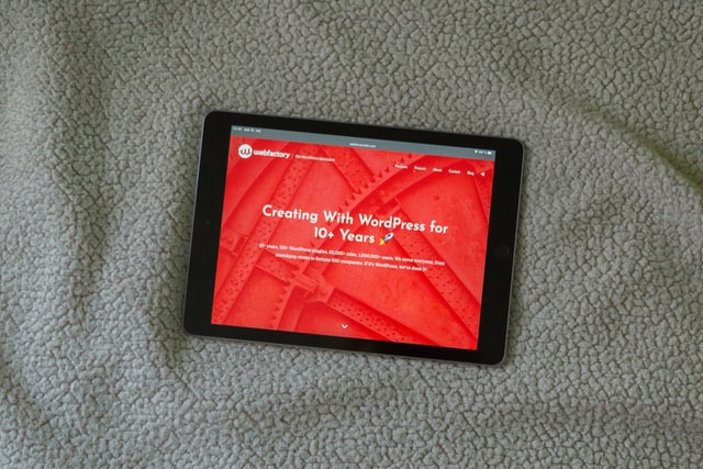 A tablet displays a website with white text on a red background. This is an example of low contrast text as explained in the WebAIM Million Analysis.
