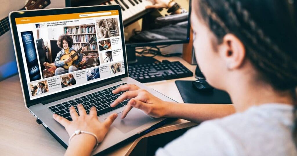 A woman looking at her computer taking an online guitar class.