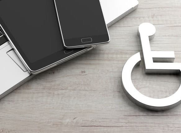 A wheelchair placard next to a laptop and cellphone, implying digital accessibility